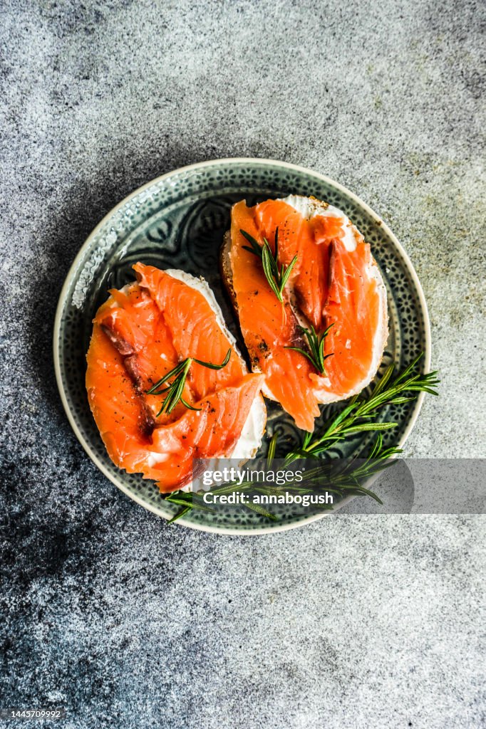 Overhead view of two smoked salmon and cream cheese toasts with rosemary