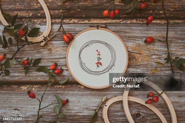 overhead view of embroidery hoop on wooden table with rosehips - embroidery frame stock pictures, royalty-free photos & images