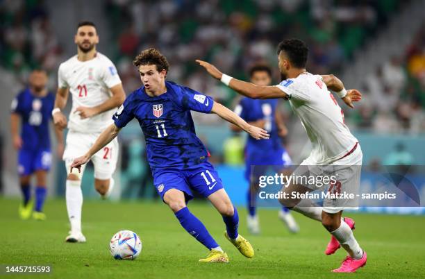 Brenden Aaronson of USA is challenged by Ramin Rezaeian of Iran during the FIFA World Cup Qatar 2022 Group B match between IR Iran and USA at Al...