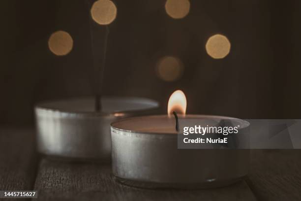 close-up of two tea light candles on a wooden table - extinguir fotografías e imágenes de stock