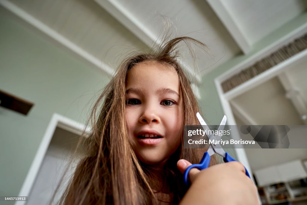A girl about 6 years old cuts off her hair.