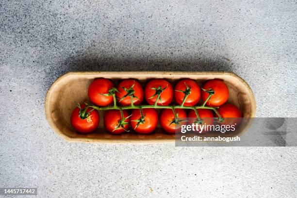 overhead view of cherry vine tomatoes in a cardboard carton - cherry tomato stock-fotos und bilder