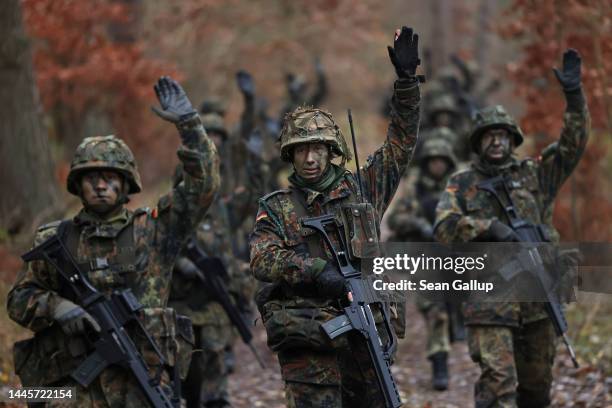 New army recruits of the Bundeswehr, Germany's armed forces, signal while on patrol during basic training in a forest on November 29, 2022 near...