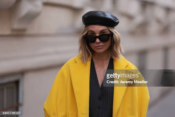 Karin Teigl is seen wearing Marc Cain barett black leather hat, Zara grey striped two piece, black sunglasses and aPrada yellow coat, on November 25,...