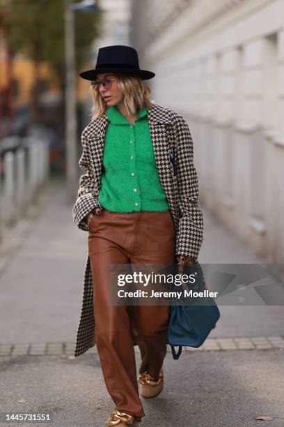 Karin Teigl is seen wearing Nomads Modern black hat, Milk green knit cardigan, Gucci NY Yankees beige checked coat, Gestuz brown leather pants, JW...