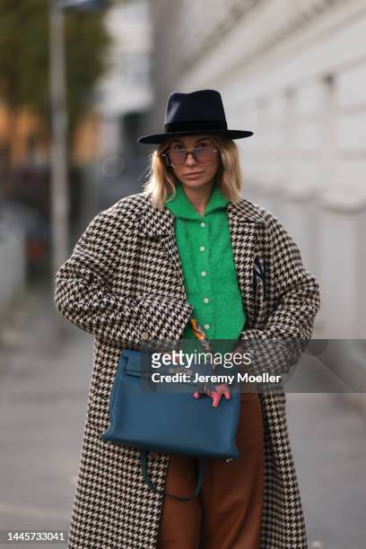 Karin Teigl is seen wearing Nomads Modern black hat, Milk green knit cardigan, Gucci NY Yankees beige checked coat, Gestuz brown leather pants,...