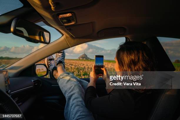 tourist woman using cellphone on rented car window driving near mont saint michel. - manche bildbanksfoton och bilder
