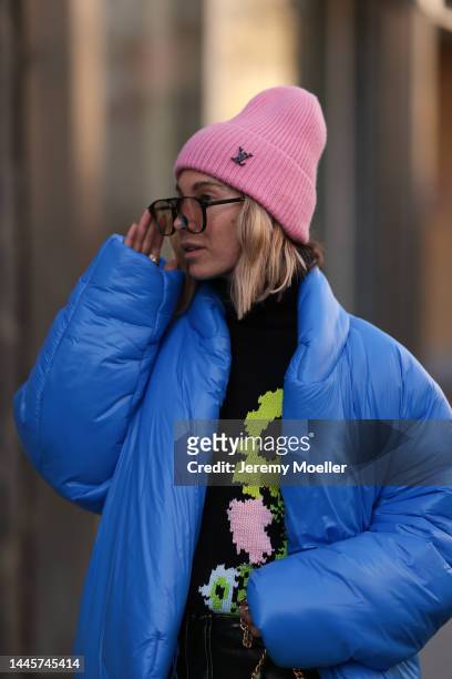 Karin Teigl is seen wearing Louis Vuitton pink wool hat, Dior sunglasses, Gap x Yeezy blue puffer jacket and H&M Studio black flower pattern sweater,...