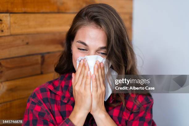 woman with a cold blowing her nose - closeup of a hispanic woman sneezing foto e immagini stock