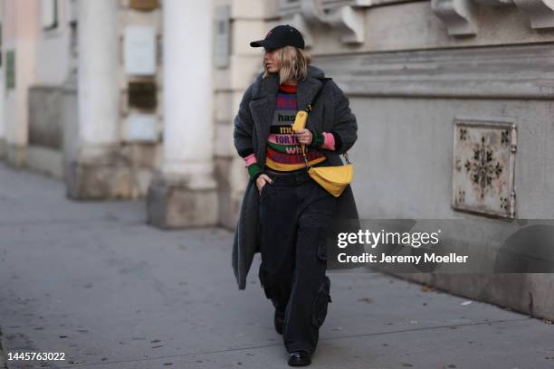 Karin Teigl is seen wearing Ami Paris black cap, Max Mara grey teddy coat, Etro colorful knit sweater, Source Unknown black cargo pants, Gucci black...