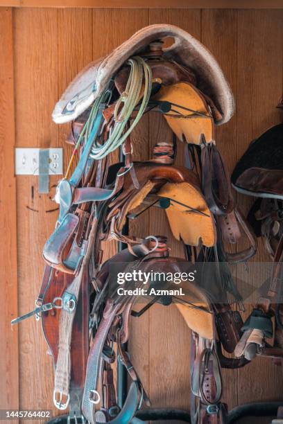 horse saddles stacked up on a wall - saddle stock pictures, royalty-free photos & images