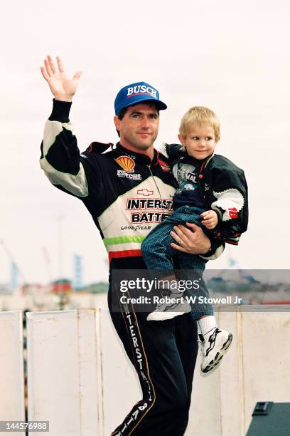 American race car driver Bobby LaBonte holds a child and waves at the Winston Cup Race at the Charlotte Motor Speedway, Charlotte, North Carolina,...