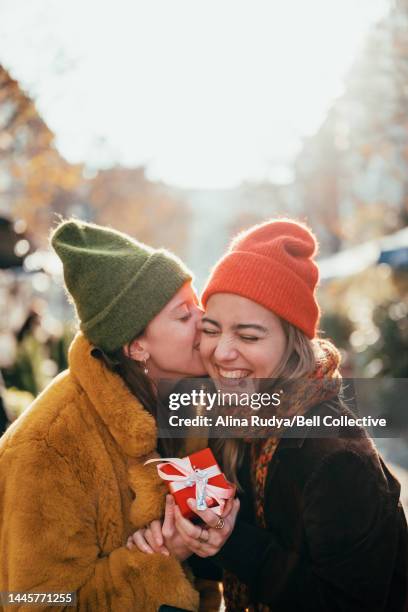 woman kissing her girlfriend on a cheek - women kissing stock pictures, royalty-free photos & images