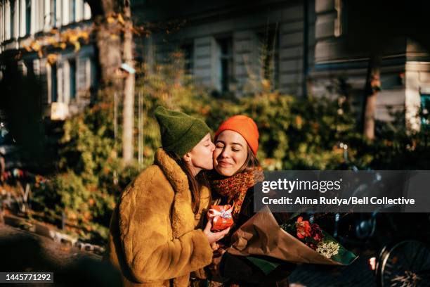 woman kissing her girlfriend on a cheek on a street - central europe stock pictures, royalty-free photos & images