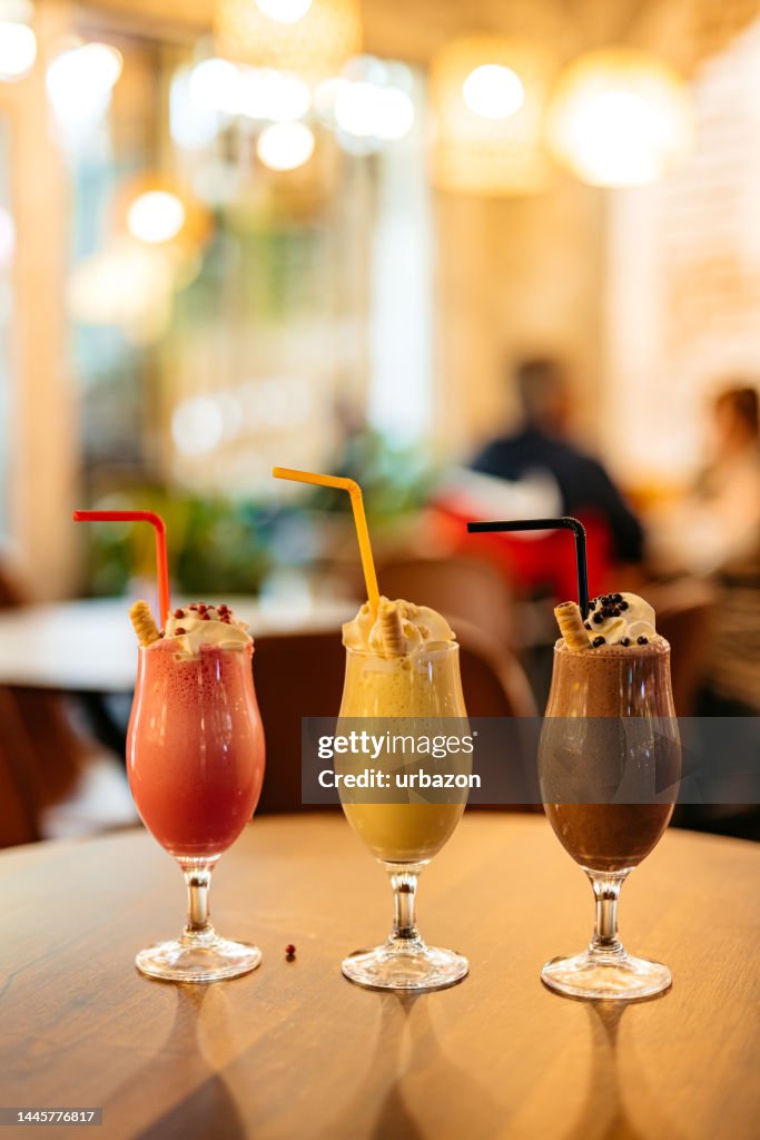 Strawberry, Vanilla And Chocolate Milkshake On A Table In A Café