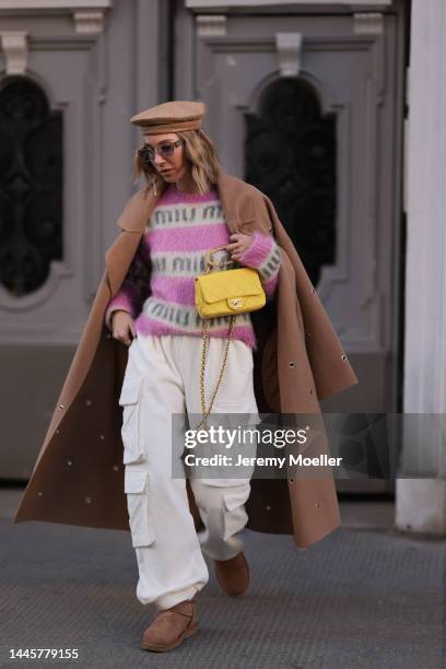Karin Teigl is seen wearing Chanel yellow leather bag, Lala Berlin beige long coat, Miu Miu knit pink/white logo sweater, Max Mara beige barett hat,...