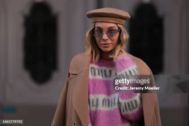 Karin Teigl is seen wearing Lala Berlin beige long coat, Miu Miu knit pink/white logo sweater, Max Mara beige barett hat and Miu Miu lilac...