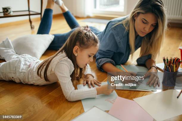 femme passant du bon temps avec une petite fille à la maison et ils dessinent ensemble - nurse photos et images de collection