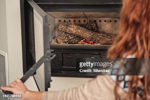 Woman hand opening wood-burning stove