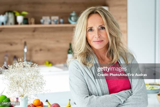 portrait of middle-aged woman looking at camera standing in kitchen - blonde business woman not looking at camera stock pictures, royalty-free photos & images