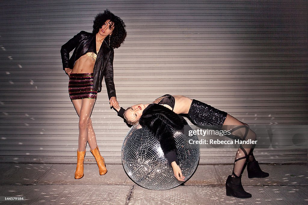 Two ladies on street with huge disco ball at night