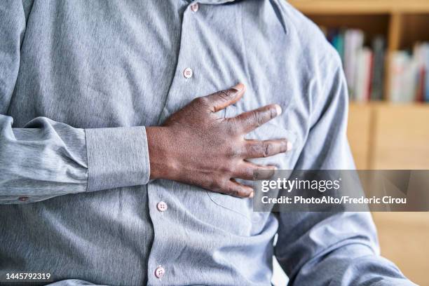 close-up shot of african-american man with hand on chest - herzinfarkt stock-fotos und bilder