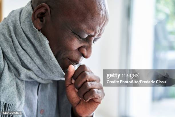 senior african-american man wearing a scarf and coughing in his hand - cough stock-fotos und bilder