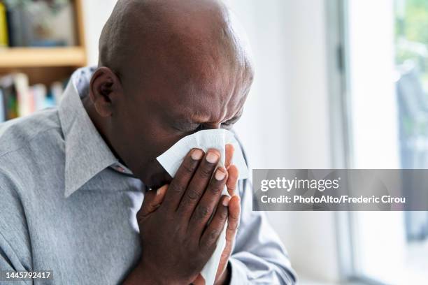 close-up shot of senior african-american man with a cold blowing his nose - virus grippe stock pictures, royalty-free photos & images