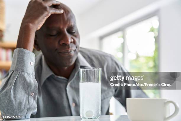 middle-aged african-american man with headache taking his medicine - cough lozenge stock pictures, royalty-free photos & images