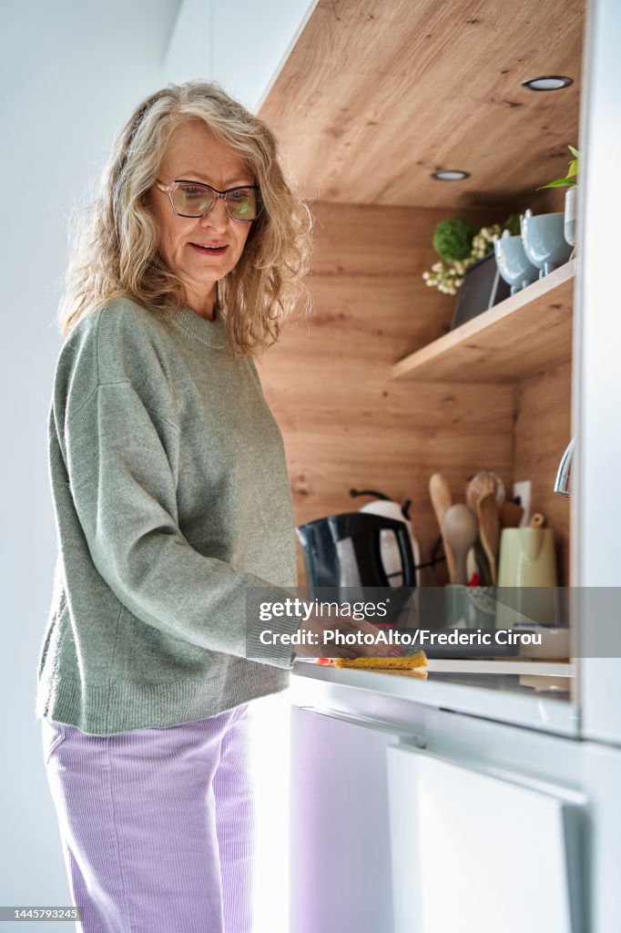 Senior woman cleaning kitchen with sponge