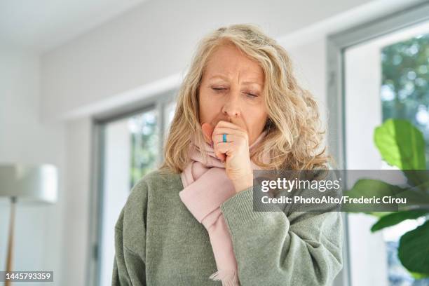 senior woman sitting indoors while coughing - haemophilus influenzae fotografías e imágenes de stock