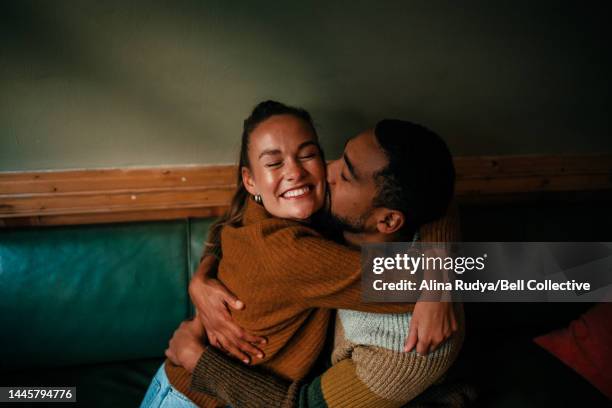 young couple hugging in a cafe - caricia fotografías e imágenes de stock