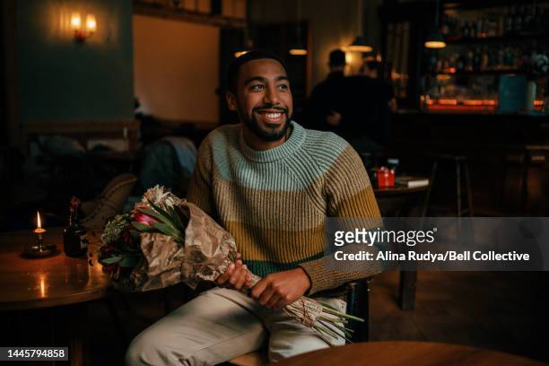 young man with a bouquet waiting in a cafe - man waiting foto e immagini stock