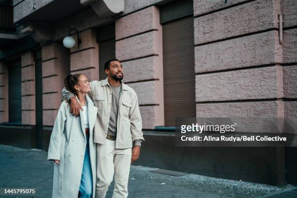 young stylish couple walking in a city - walk city stock-fotos und bilder