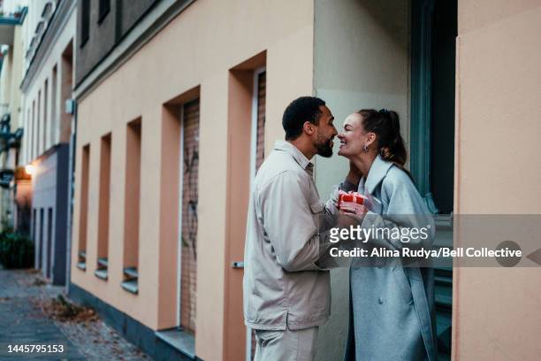 couple with a holiday present on a doorstep - couples romance imagens e fotografias de stock