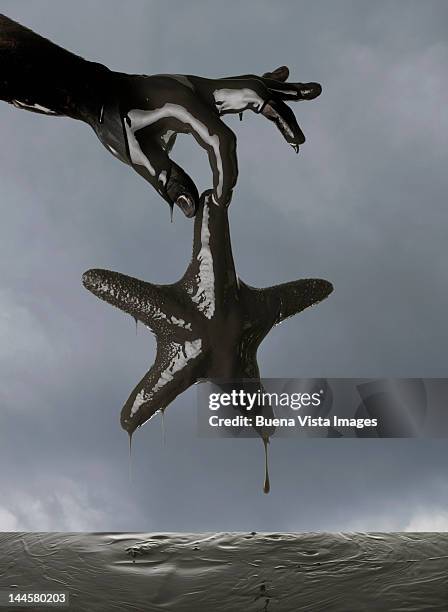 man pulling starfish out of oil - petrolio 個照片及圖片檔