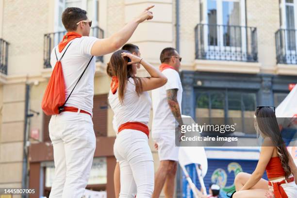 low angle rear view of a group of people standing in the street at the san fermines festival in pamplona - stierenrennen stockfoto's en -beelden