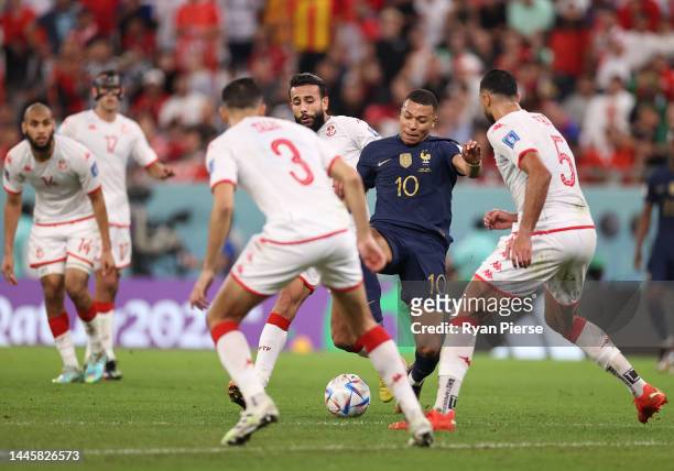 Kylian Mbappe of France is challenged by Tunisia defenders during the FIFA World Cup Qatar 2022 Group D match between Tunisia and France at Education...