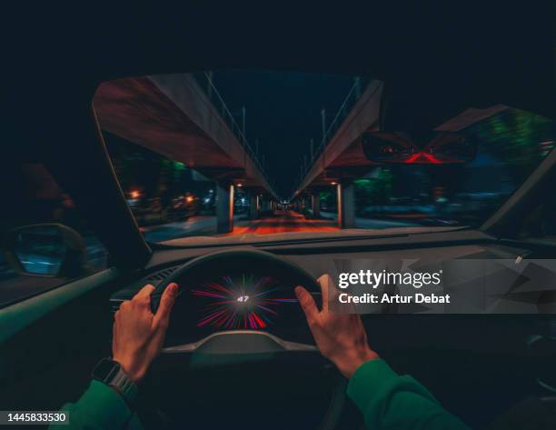 driving an electric car at night in stunning urban scenario with dramatic effect. pov. - perspectiva de un coche fotografías e imágenes de stock