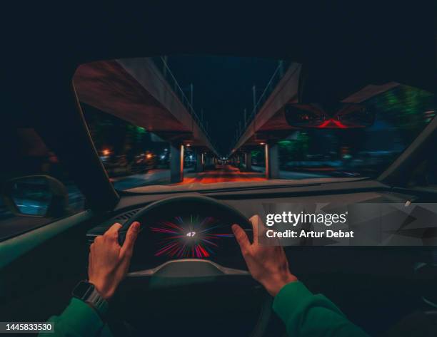 driving an electric car at night in stunning urban scenario with dramatic effect. pov. - cruscotto foto e immagini stock