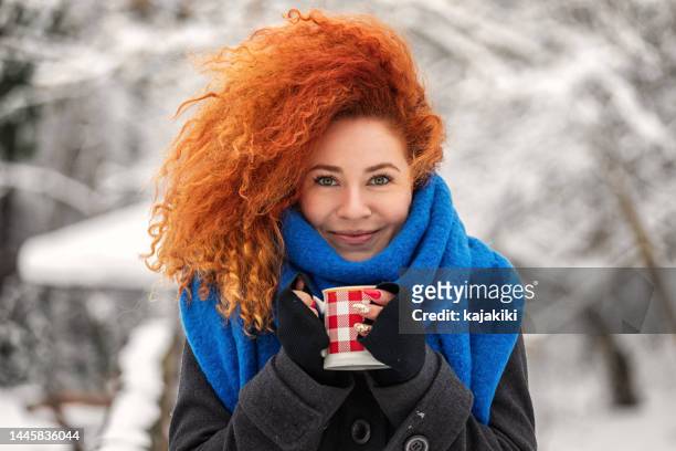 beautiful young woman in coat drinking hot cocoa in winter forest - january 24 stock pictures, royalty-free photos & images