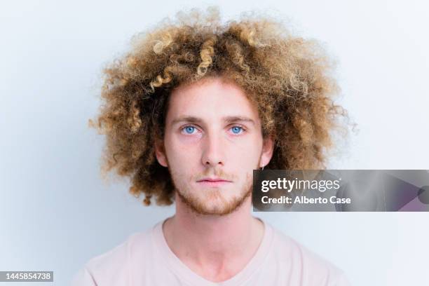 close-up of a man with curly hair looking at the camera - young face serious at camera stockfoto's en -beelden