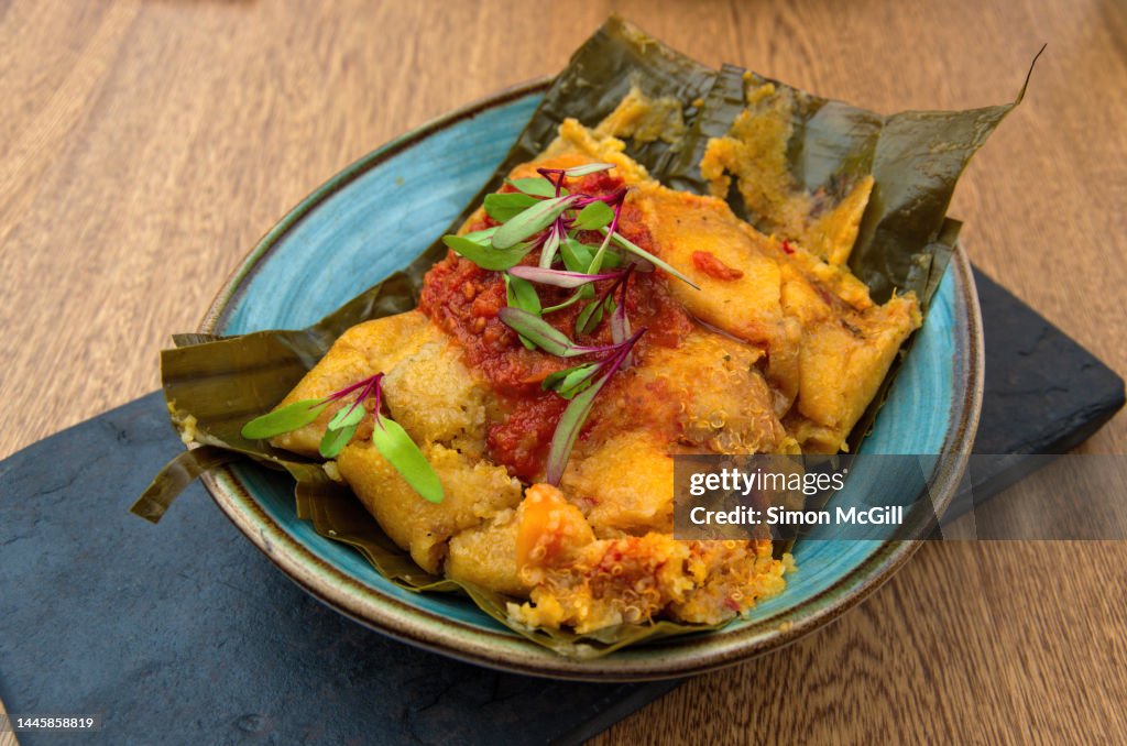 Tamal con harina de arroz y quinoa, guiso criollo, zanahoria, costilla de res y pollo campesino (Tamale with rice flour and quinoa, creole stew, carrots, beef ribs and country chicken) on a slate serving platter