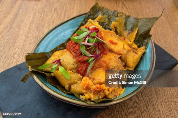 tamal con harina de arroz y quinoa, guiso criollo, zanahoria, costilla de res y pollo campesino (tamale with rice flour and quinoa, creole stew, carrots, beef ribs and country chicken) on a slate serving platter - harina bildbanksfoton och bilder