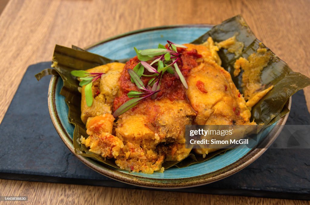 Tamal con harina de arroz y quinoa, guiso criollo, zanahoria, costilla de res y pollo campesino (Tamale with rice flour and quinoa, creole stew, carrots, beef ribs and country chicken) on a slate serving platter