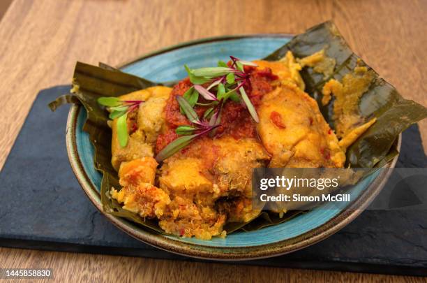 tamal con harina de arroz y quinoa, guiso criollo, zanahoria, costilla de res y pollo campesino (tamale with rice flour and quinoa, creole stew, carrots, beef ribs and country chicken) on a slate serving platter - zanahoria stock pictures, royalty-free photos & images