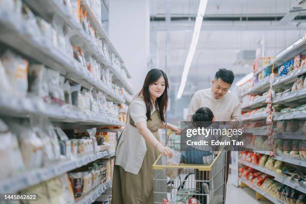 junge asiatische chinesische familie, die lebensmittel in der kühlabteilung des supermarkts kauft - asian family shopping stock-fotos und bilder
