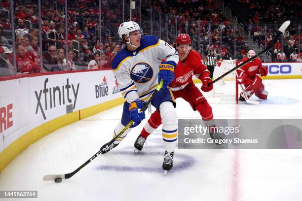 Tage Thompson of the Buffalo Sabres looks to pass around Moritz Seider of the Detroit Red Wings during the first period at Little Caesars Arena on...