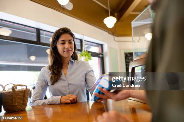 woman making a mobile payment at a cafe - mobile payment cafe stock pictures, royalty-free photos & images