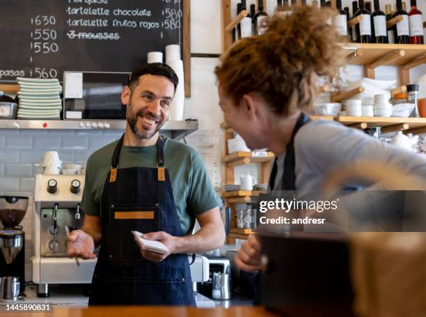 happy workers at a cafe talking and laughing - bakery apron stock pictures, royalty-free photos & images